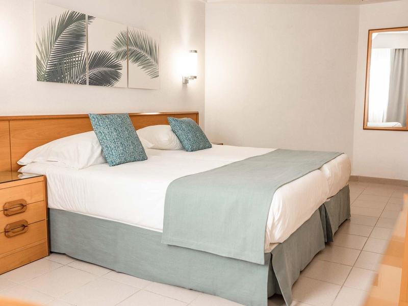 Nowoczesny pokój hotelowy z łóżkiem podwójnym i niebiesko-zielonymi akcentami.