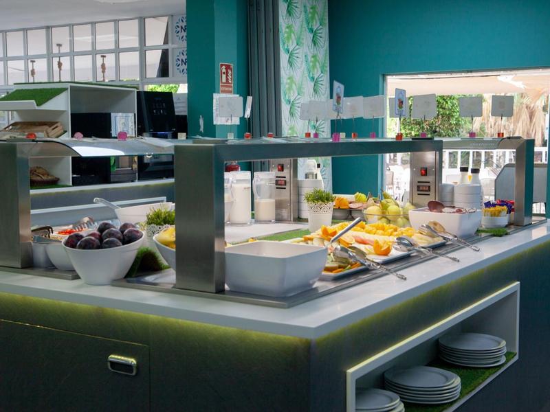 Bufé con varios platos en un restaurante moderno con grandes ventanas.