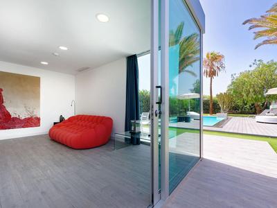 Moderne binnenruimte met een rood zitzak, grote ramen en uitzicht op een zwembad en tuin