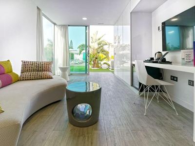 Lichte woonkamer met gebogen bank, kattengrot tafel en bureau naast terras met uitzicht op zwembad.