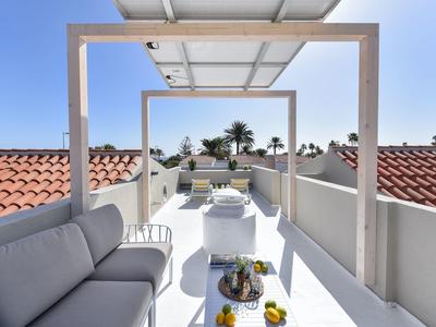 Moderne dakterras met comfortabele zitplaatsen en uitzicht op rode pannendaken.