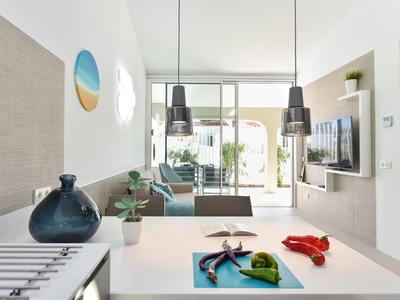 Moderne keuken en woonruimte met eiland, planten en toegang tot de tuin.