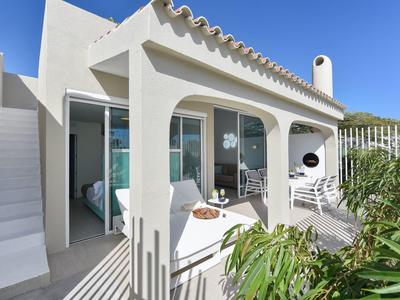 Moderne witte bungalow met terras en zithoek onder een blauwe lucht