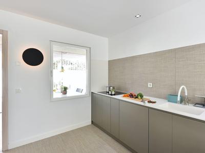 Moderne hotelkeuken met grijze kasten, wit aanrecht en minimalistisch ontwerp.