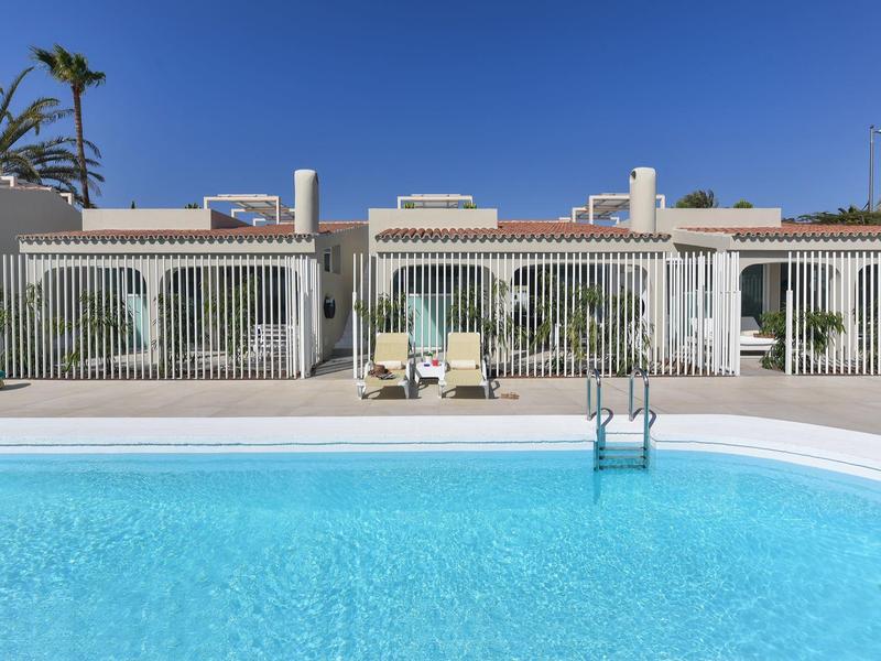 Helder zwembad voor eenlaagse vakantiewoningen onder een zonnige hemel.