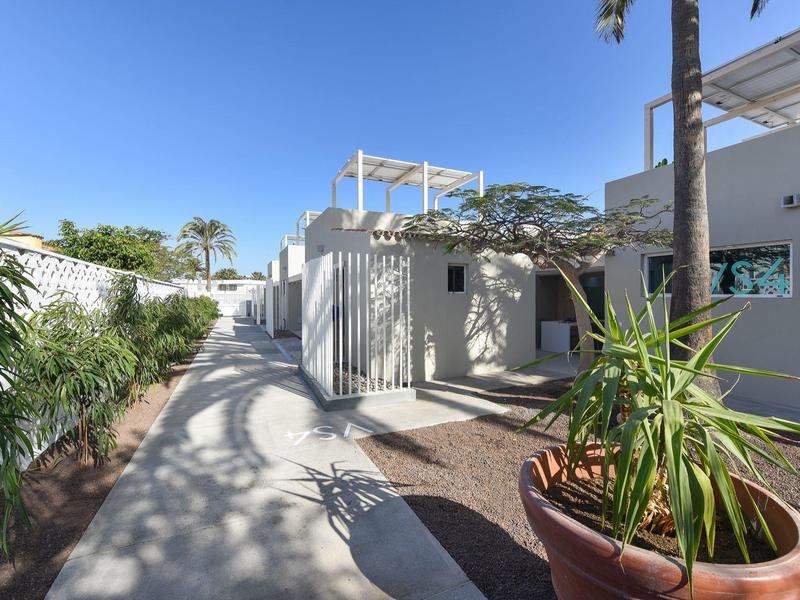 Moderne hotel buitenruimte met pad, palmbomen en heldere blauwe lucht