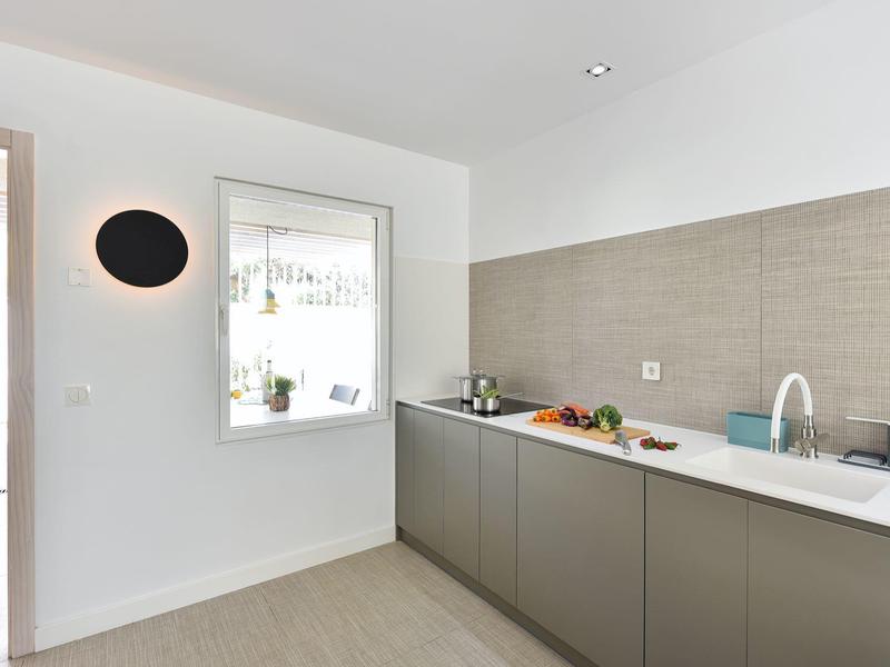 Moderne hotelkeuken met grijze kasten, wit aanrecht en minimalistisch ontwerp.