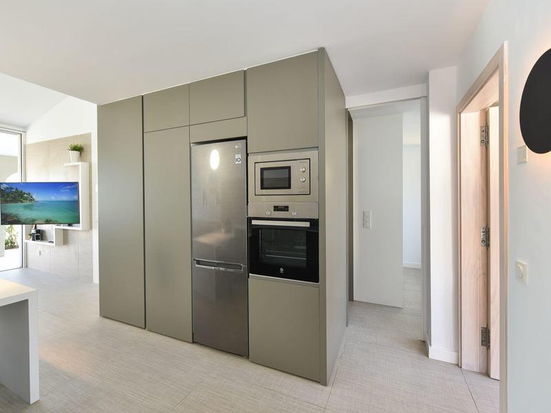 Moderne keuken met ingebouwde zilveren apparaten in lichte, minimalistische ruimte.