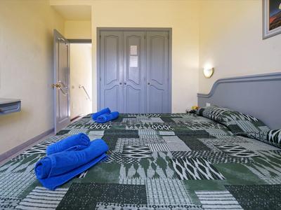 Gezellige hotelkamer met tweepersoonsbed, grijs meubilair en blauwe handdoeken.