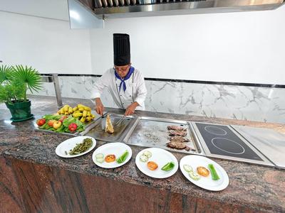 Kok met zwarte hoed bereidt meerdere borden eten in een moderne hotelkeuken.