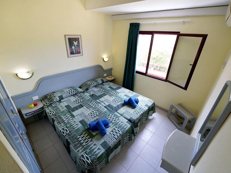 Gezellige hotelkamer met twee bedden, raam, spiegel en airconditioning.