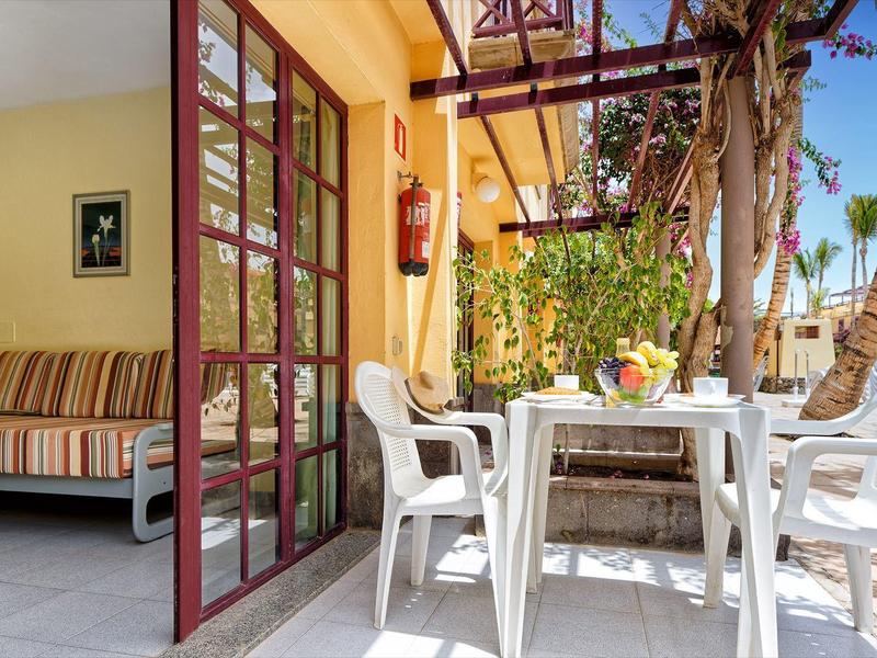 Knusse terras met witte tafel en stoelen buiten een kamer met banken.
