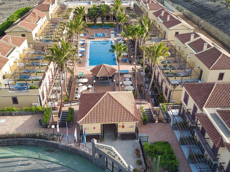 Luchtfoto van een hotel met zwembad, palmbomen en toegang tot het strand.