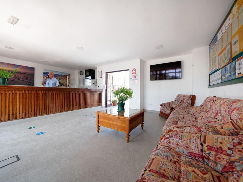 Lichte hotel lobby met receptie, zithoek en informatiebord.