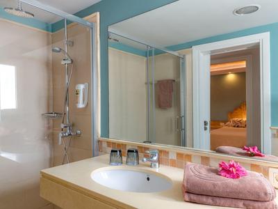 Modernes Badezimmer mit beigem Waschbecken, großem Spiegel und türkisfarbenen Wänden.