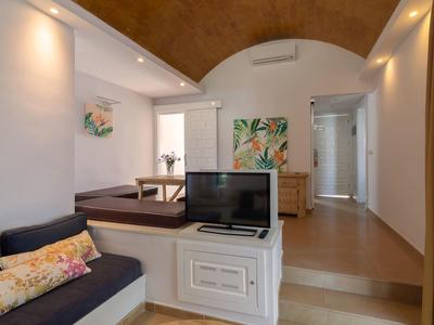 Gemütliches Wohnzimmer mit Sofa, TV, natürlicher Beleuchtung und dekorativer Wandgestaltung.