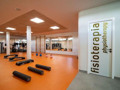 Sala terapia moderna con tappetini e attrezzature fitness in una clinica di fisioterapia.