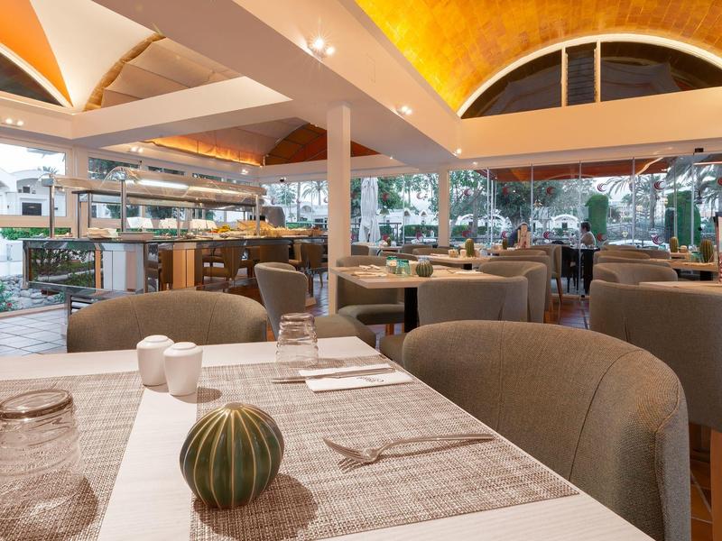 Modernes Restaurant mit bequemen Sesseln, gedeckten Tischen und großen Fenstern, warm beleuchtet.