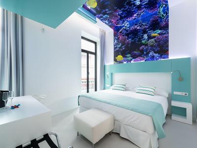 Camera d'hotel moderna con decorazioni blu e bianche e parete acquario.