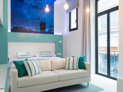 Soggiorno luminoso con divano accogliente, cuscini, macchina da caffè e porta balcone con vista esterna.