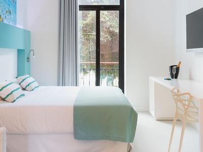 Lichte hotelkamer met twee bedden, tv aan de muur en bureau met stoel.