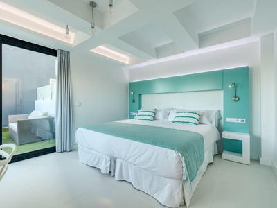 Camera d'hotel luminosa e moderna con letto grande e accesso a una terrazza.