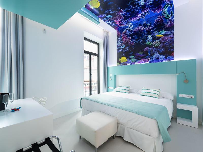 Camera d'hotel moderna con decorazioni blu e bianche e parete acquario.