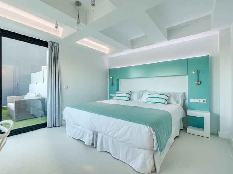 Camera d'hotel luminosa e moderna con letto grande e accesso a una terrazza.