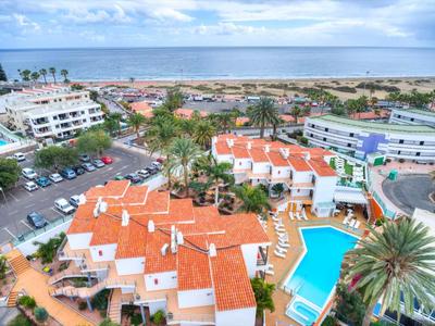 Uitzicht op een hotel met rode daken, zwembad en aangrenzend strand aan zee