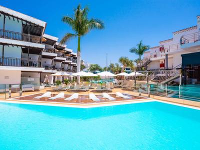 Hotelpool mit Liegestühlen und Palmen unter klarem blauem Himmel