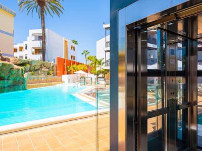 Modern zwembad met waterval en palmbomen in een zonnige hotelomgeving.