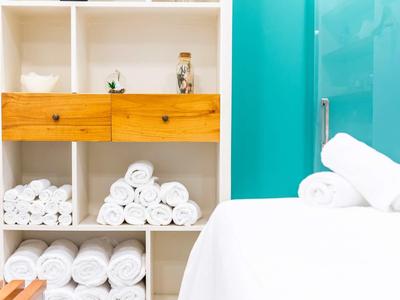 Witte handdoekstapels en houten meubels tegen een turquoise muur in een spa- of hotelkamer.