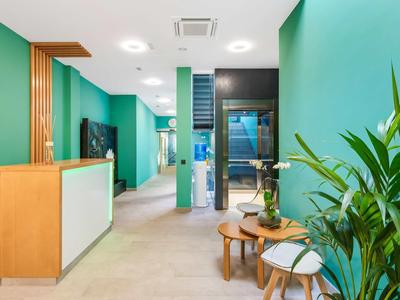 Moderne hotel lobby met groene muren, planten en houten balie.