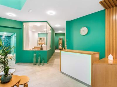 Moderne receptieruimte met groene muuraccent, houten details en gezellige zitplaats.