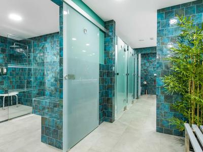 Moderne wellnessruimte met blauwe tegels, douches en groene planten