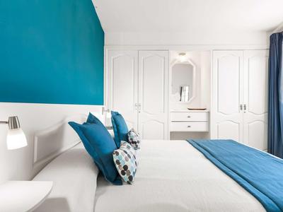 Modern hotelkamer met blauw-witte kleuren en groot bed.