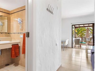 Uitzicht vanuit badkamer naar lichte woonkamer met balkon en planten