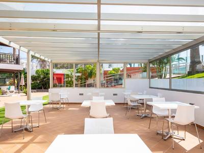 Overdekte buitenruimte met witte stoelen en tafels in een moderne hotelomgeving.