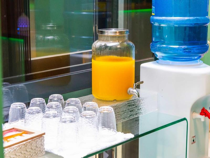 Sapdispenser en waterkoeler met glazen bekers op een hoteltafel.