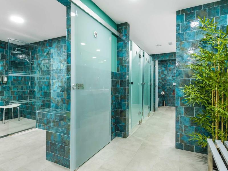 Moderne wellnessruimte met blauwe tegels, douches en groene planten