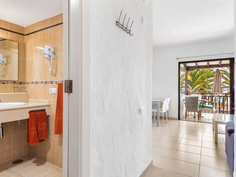 Uitzicht vanuit badkamer naar lichte woonkamer met balkon en planten