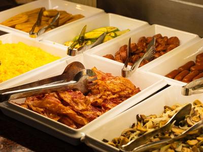 Bufet z boczkiem, kiełbaskami, jajecznicą i grillowanymi warzywami w białych tackach.