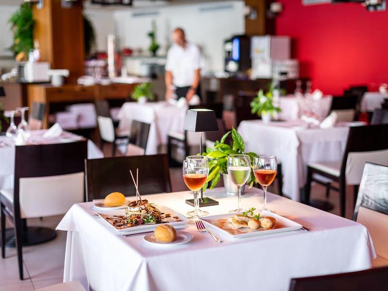 Stoły z białymi obrusami, napojami i przystawkami w restauracji.