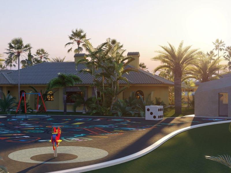 Area esterna soleggiata con parco giochi e palme davanti a un edificio dell'hotel.