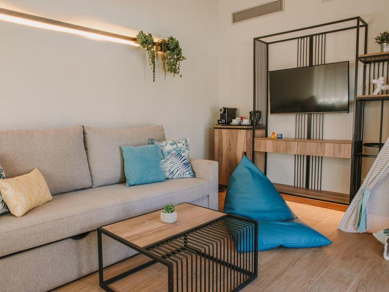 Soggiorno accogliente con divano grigio chiaro, cuscini colorati e tavolino moderno.