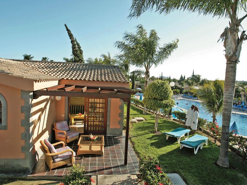 Accogliente terrazza vicino alla piscina con lettini e ombrelloni in un resort tropicale.