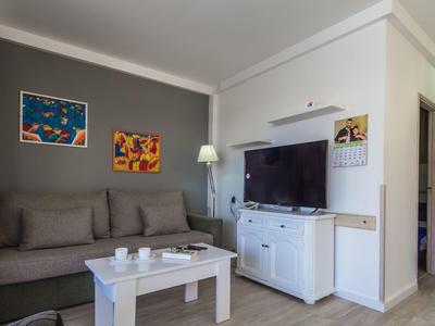 Salon moderne avec canapé gris, table basse blanche et TV sur meuble blanc.