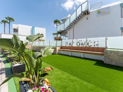 Grüner Gartenbereich mit Bänken und moderner weißer Architektur bei sonnigem Wetter
