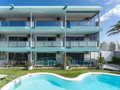 Modernes Hotelgebäude mit Balkonzimmern und einem Schwimmbecken im Vordergrund.
