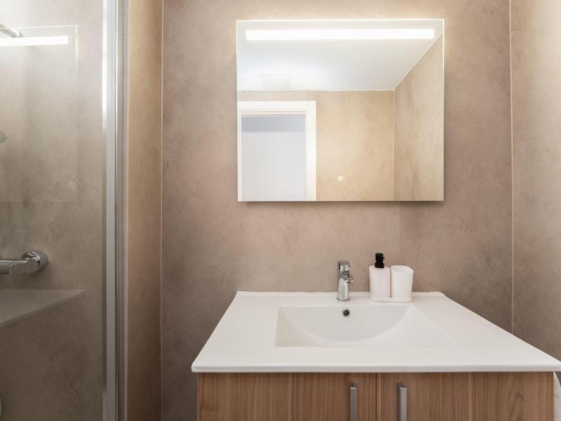 Moderner Badezimmerwaschtisch mit Spiegel und Dusche in hellen Farben